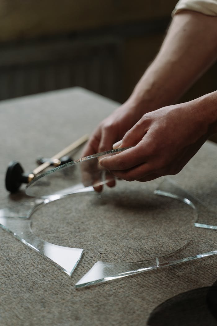 Close-up of an artisan cutting glass circles indoors, showcasing craftsmanship and skill.